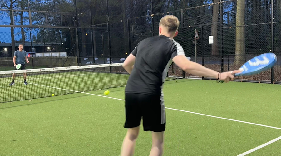 Action shot of two men playing padel tennis on a green court.