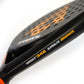 Close up of the side of a black and orange Karakal padel tennis racket on a white background.