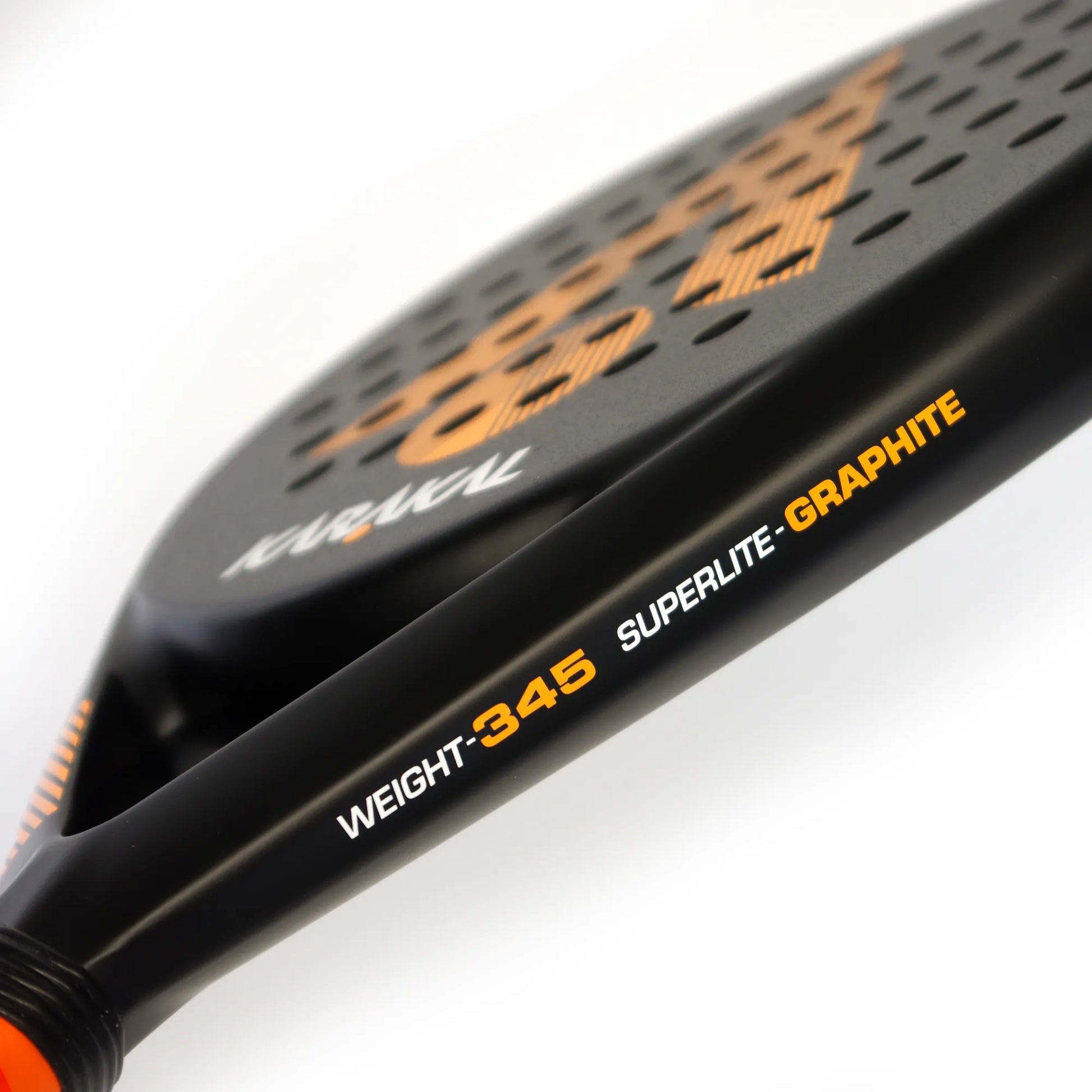 Close up of the side of a black and orange Karakal padel tennis racket on a white background.