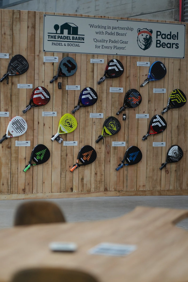 A display of padel rackets on a wooden wall at a padel tennis venue.