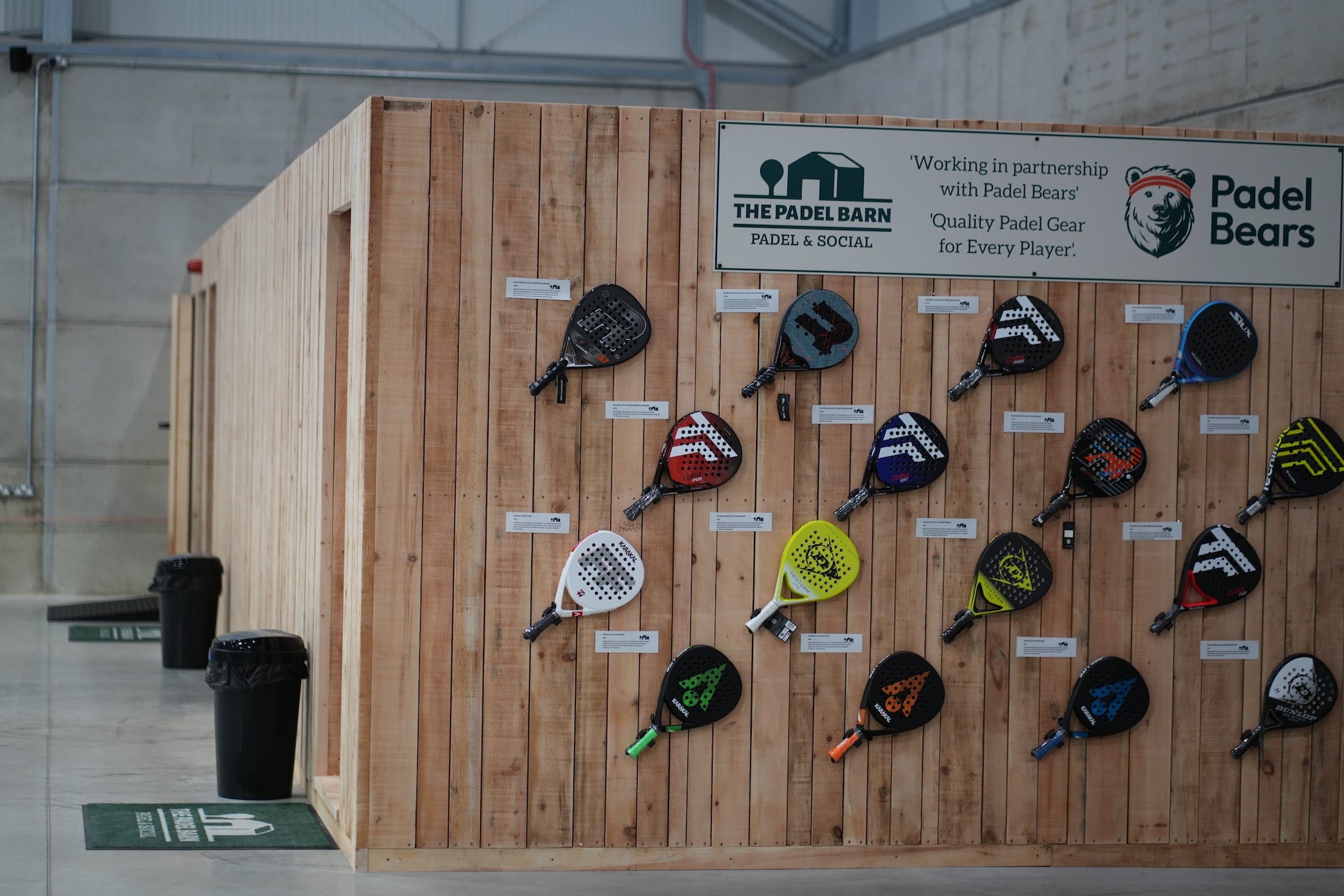 A display of padel rackets on a wooden wall at a padel tennis venue.