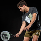 Action shot of a man with a grey Royal Padel Efe Extreme padel racket with green and black branding on a black background.