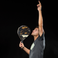A man holding a black and gold Royal Padel Anniversario padel racket on a black background.
