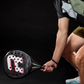 Action shot of a man using a black, white and red Royal Padel Whip padel racket on a black background.
