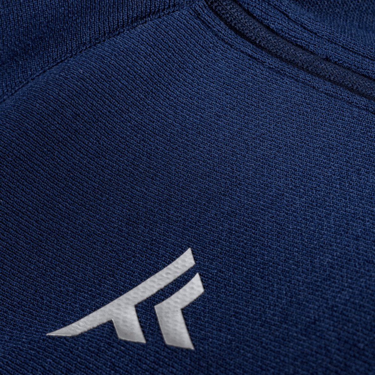 Navy blue fabric with a silver logo on a close-up view of a sports jacket