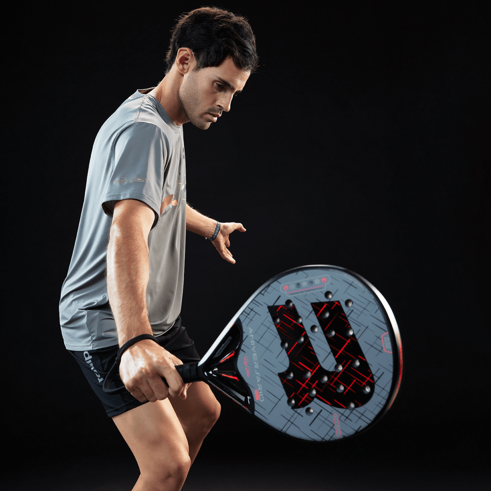Man holding a Royal padel racket with a black background