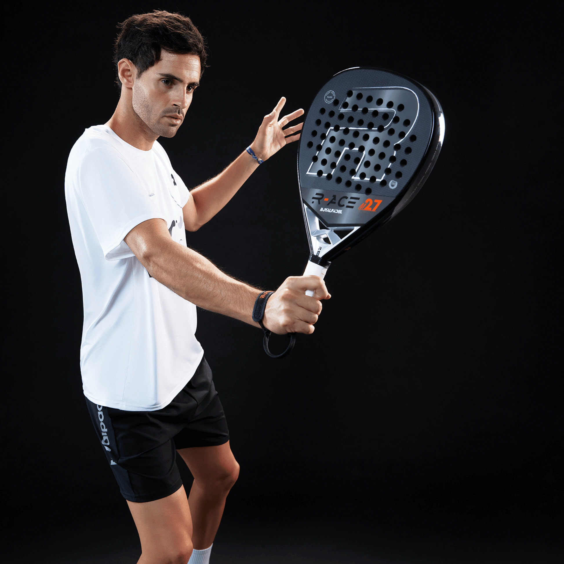 Man holding a Royal Padel M27 R ace black and gray racket against a black background