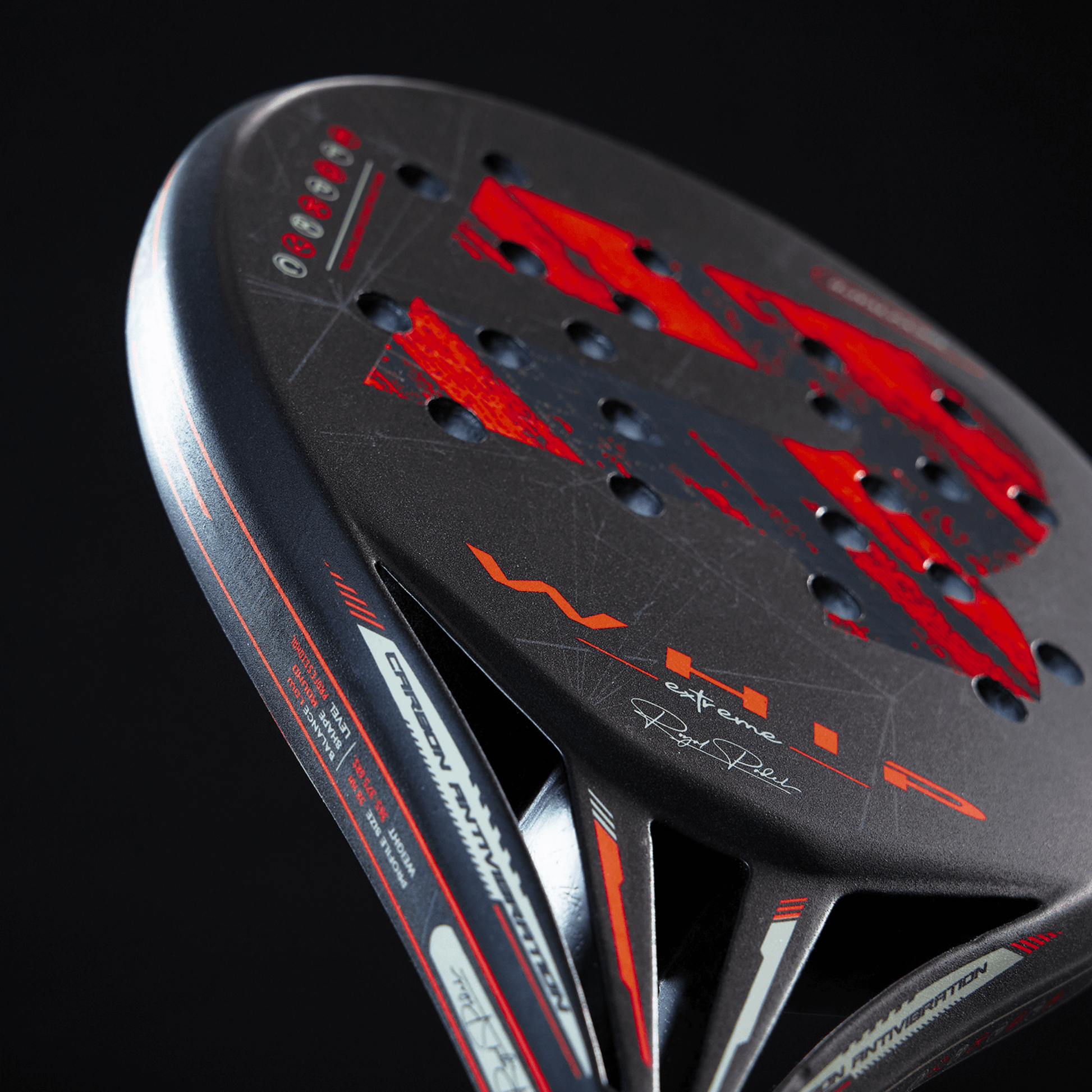 Close-up of a black and red Royal Padel racket with branding on a dark background
